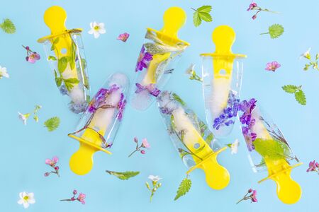 Flying ice-cream with flowers on blue pastel table. Fresh bright summer background.