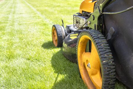 Lawn mower on fresh green lawn, freshly cut grass on summer sunny dayの写真素材