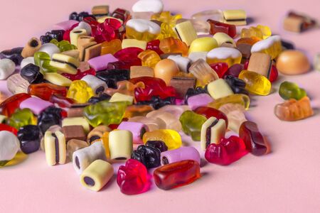 Colorful candy on pink background. Chewing sweets on light table. Top view, flat lay, copy spaceの写真素材