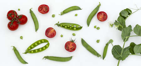 Red cherry tomatoes and green peas on white wooden table. Fresh summer vegetables for food concept, top view, flat lay, bannerの写真素材