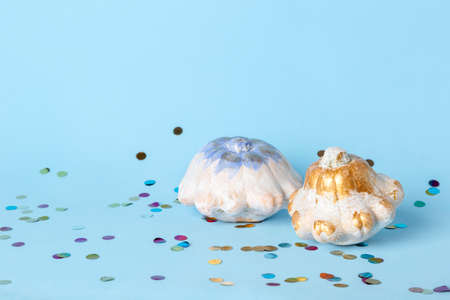 Halloween decoration with white pumpkins and colorful confetti on blue background. Thanksgiving...