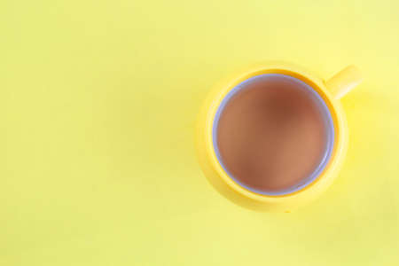 Yellow cup of hot tea on yellow background, top view, flat layの写真素材