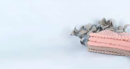 Pile of pink knitted cashmere scarves, sweaters on light blue background. Folded autumn and winter...