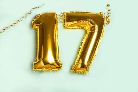 Decoration for seventeen birthday party. Golden balloon in form of 17 number on blue background.の写真素材