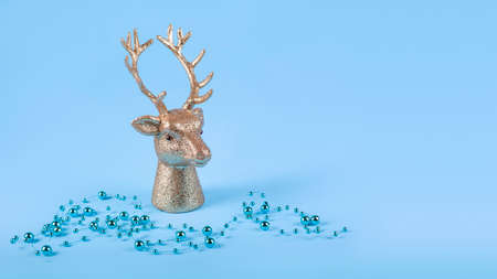 Christmas composition in minimal style - golden deer head on blue background with New Year balls, lights. Copy space.の写真素材