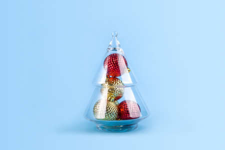 Decorative Christmas balls in glass tree on blue background.