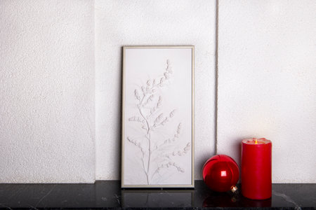 Botanical bas-relief wildflowers for wall art and red christmas ball and candle on marble shelf. 3D Flower plaster decor. Christmas decoration. Stylish and modern interior of room.の写真素材
