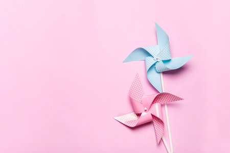 Pink blue paper spinners on light pink background. Kids toys colorful pinwheels on celebration party...