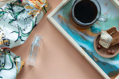 Womens accessories - perfume, scarf, cup of coffee with biscuit on tray. Mockup for elegant concept....