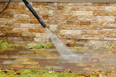 Man cleaning street with high pressure power washer, washing stone garden paths. High quality photoの写真素材