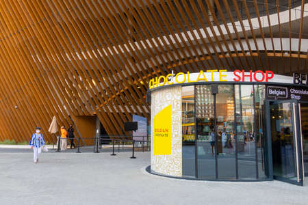 People walk along paths between pavilions. Exhibition Hall Poland in evening rays of sunset.のeditorial素材