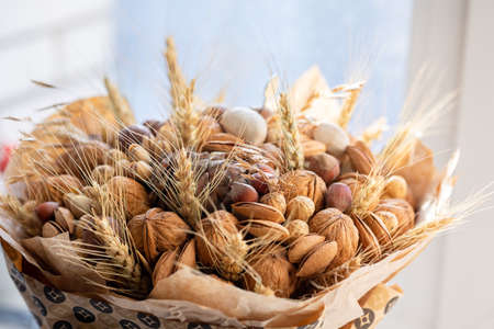 Handmade bouquet of nuts, pine cones, spikelets for holiday. Food floristry. Gift for men. Edible bouquet for birthday, valentine's day. Selective focus. High quality photoの写真素材