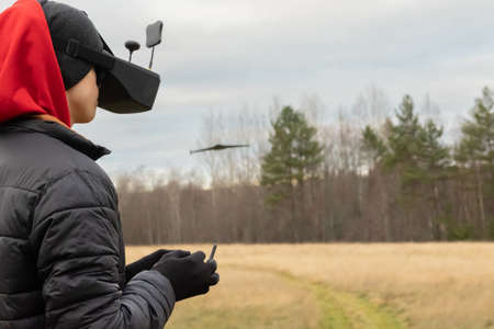 Young man launches rc plane into sky. Teenager with glasses playing with toy radio-controlled...