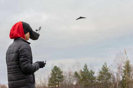 Young man launches rc plane into sky. Teenager with glasses playing with toy radio-controlled airplane outdoors. Boy holding radio remote controller.の写真素材