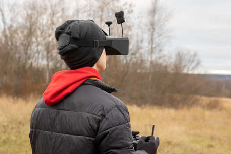 Young man launches rc plane into sky. Teenager with glasses playing with toy radio-controlled...