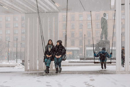 Moscow, Russia - April 2, 2022: Snowfall in Moscow. Happy people swing on hanging swings near Mayakovskaya metro stationのeditorial素材
