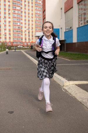 Back to school. Girl in school uniform go to school with backpack behind their backs. Beginning of...