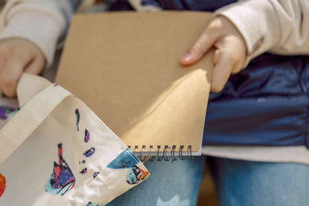 Little girl paints in open air in spring blooming fairytale park. Childrens drawings. Creative kid. Joy of childhood. High quality photoの写真素材