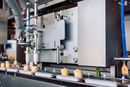 Manufacturin for automatic production of ice cream cones. Conveyor belt in waffle cups, creme...