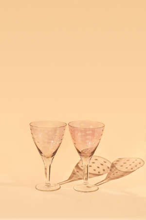 Empty glasses for wine stand on light background in sunlight with shadows. High quality photoの写真素材