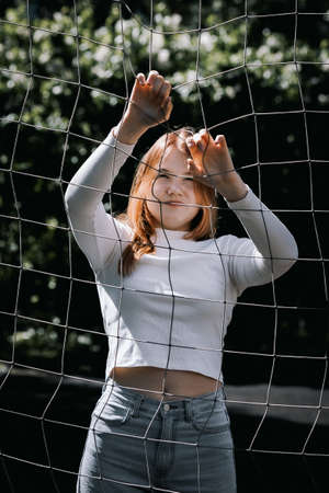 Portrait of pretty girl with long hair near volleyball net on background of nature. High quality photoPortrait of pretty girl with long hair near volleyball net on background of natureの写真素材