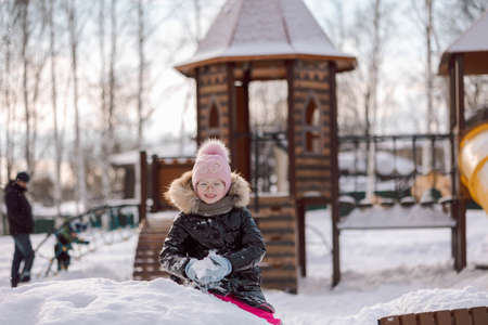 Little girl walks outdoors on winter snowy day in park. High quality photo