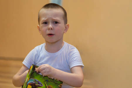 Little boy cries from grief and resentment. He wipes tears from his cheek with his hand. High quality photoの写真素材