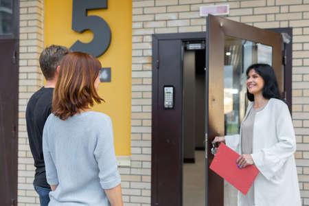 Real estate agent shows apartment in new building, handing keys to young couple. Concept new homes,...