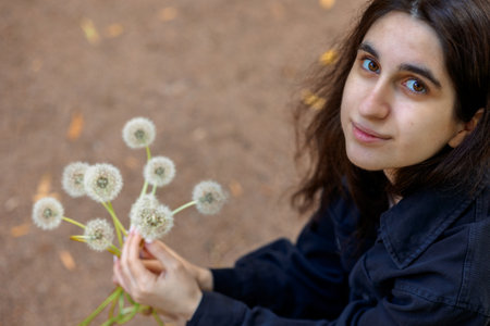 Wreath of white dandelions. Step by step instructions. Step 2. Female holding bouquet of white airy dandelion flowers. High quality photoの写真素材