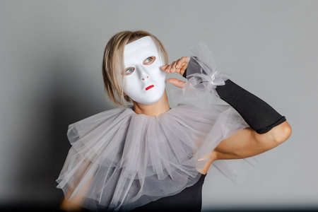 Woman in white theater mask and harlequin collar on gray background. Fancy dress, masquerade...