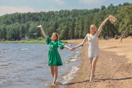 Smiling girls walking along coastline. Concept of friendship, entertainment and fun. High quality photoの写真素材