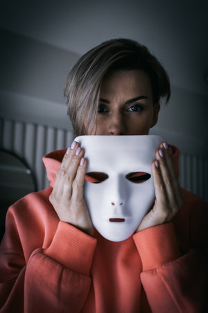 Portrait of woman in white theater mask on black background. Concept of mental disorders, human...