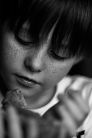 Portrait of boy with Red bearded Agama iguana. Little child playing with reptile. Selective focus. Black and white photography. High quality photoの写真素材