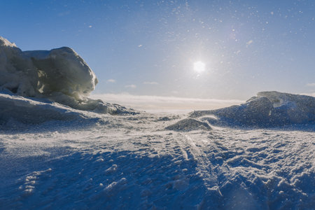 Winter landscape. Panoramic view of beautiful sunset on bay. Ice, snow and rocks on coastline. Setting sun in bright light. High quality photoの写真素材