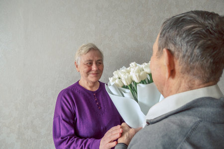 Active romantic senior husband giving his wife beauty bouquet of flowers. Dating at old ages. Happy elderly senior couple in love. High quality photoの写真素材