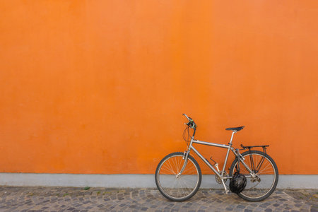 Black bicycle parked next to concrete orange wall. Banner, copy space. High quality photoの写真素材