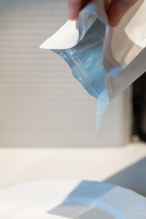 Womans hand pours flour from package into plate for cooking. High quality photoの写真素材