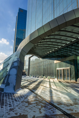 Astana, Kazakhstan - November 23, 2022: Modern architectural urbanistic entrance to skyscraper. Abstract geometric background with sun reflection and shadows. Interior building with glass windowsのeditorial素材