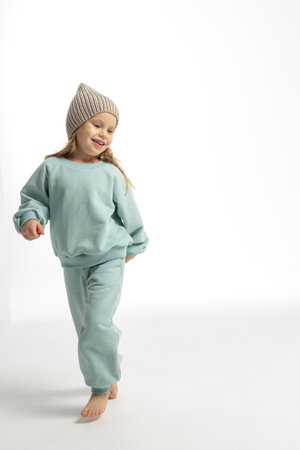 Portrait of beautiful cute little toddler girl. Child with funny face in mint sweatshirt and hat. Pretty smile kid in studio on white background.の写真素材