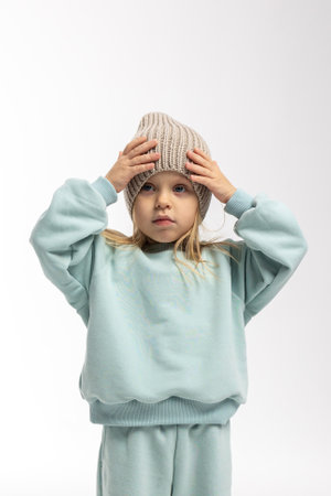 Portrait of beautiful cute little toddler girl. Child with funny face in mint sweatshirt and hat. Pretty smile kid in studio on white background.の写真素材