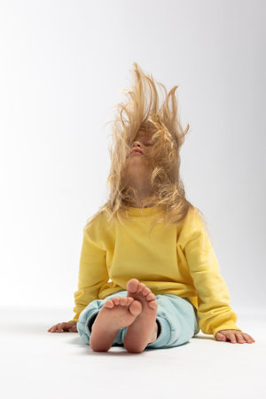 Portrait of beautiful cute little toddler girl. Child with funny face in yellow sweatshirt. Pretty smile kid in studio on white background. High quality photoの写真素材