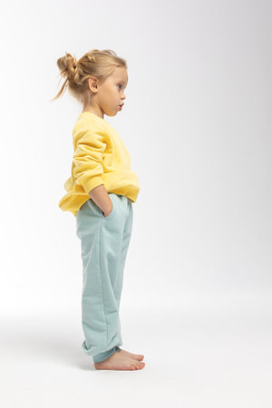 Portrait of beautiful cute little toddler girl. Child with funny face in yellow sweatshirt. Pretty smile kid in studio on white background. High quality photoの写真素材