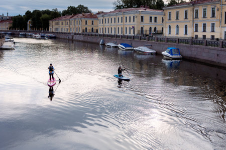 Saint Petersburg, Russia - July 13, 2023: People on SUP boards float along Moyka River in early...