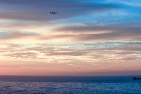 Plane in sky is landing. Beautiful sunset in sky with clouds and rays of sunの写真素材