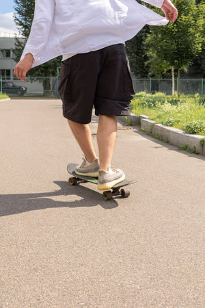 Young man in white shirt skateboarding in park. Vertical photo. High quality photoの写真素材