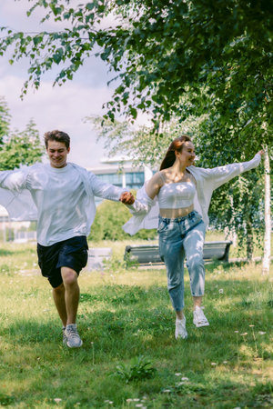 Loving couple of young girl and man are walking and having fun in park on warm summer day. Vertical photo. High quality photoの写真素材