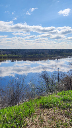 Panoramic view of river bend, forest and blue sky. Beautiful reflection of white clouds in water at...