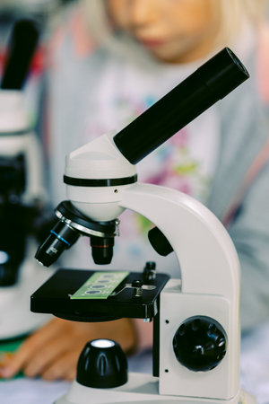 Modern white microscope on blurred background. Concept of teaching biochemistry to students and schoolchildren. Selective focus. Vertical photo. High quality photoの写真素材