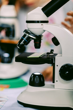 Modern white microscope on blurred background. Concept of teaching biochemistry to students and schoolchildren. Selective focus. Vertical photo. High quality photoの写真素材