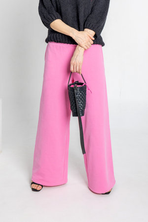 Portrait beautiful woman of model appearance. Girl in black jumper and pink trousers on grey background. Pretty female with trendy makeup posing in studio. Vertical photo.の写真素材